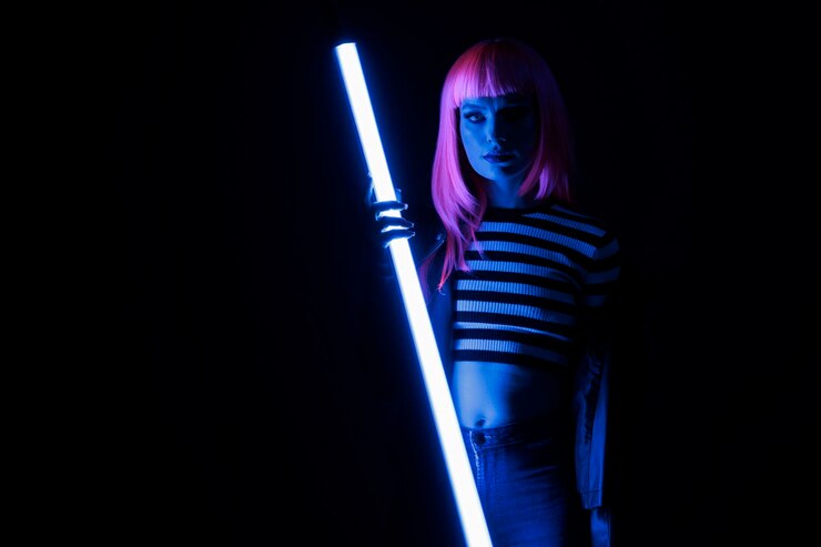 Foto retrato de una persona elegante que sostiene una luz de neón púrpura que brilla en la oscuridad, divirtiéndose con una iluminación violeta fluorescente para una pose futurista. mujer con chaqueta de cuero punk y luz de colores sobre el fondo.