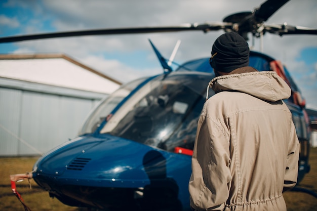 Retrato de piloto de helicóptero de pie cerca del vehículo en el aeropuerto de campo