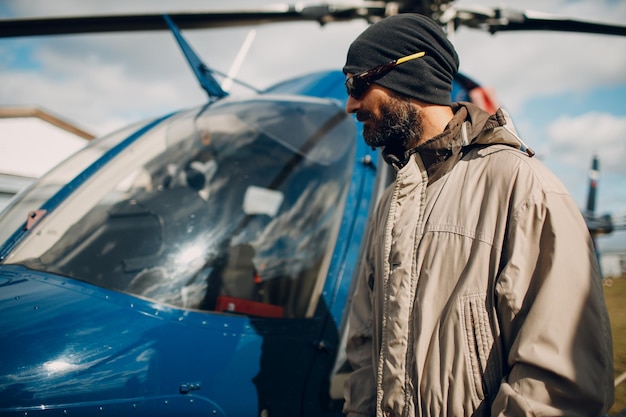 Retrato de piloto de helicóptero de pie cerca del vehículo en el aeropuerto de campo