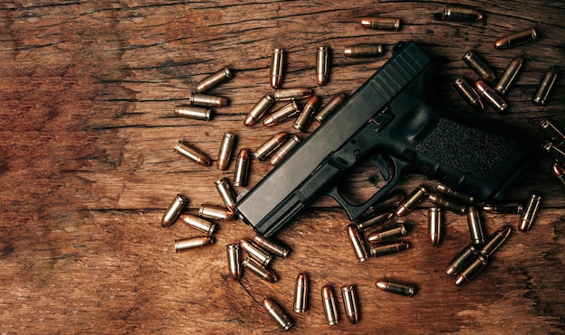 Retrato de una pistola negra de 9 mm en un viejo piso de madera con munición de 9 mm al lado de la vista superior