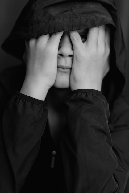 Retrato preto e branco de um adolescente em fundo escuro Foto baixa de um jovem adolescente Fotografia em preto e branco Foco seletivo