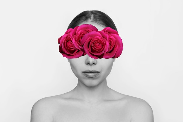 Foto retrato preto e branco de uma jovem com flores rosa de cor rosa no rosto escondendo os olhos