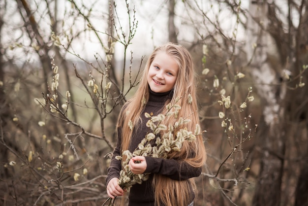 Retrato de primavera de una hermosa niña con un sauce en flor