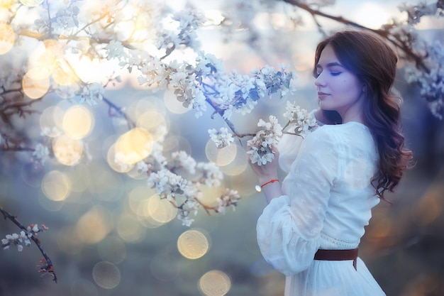 retrato de primavera de una mujer adulta feliz en un jardín floreciente, rayos de sol y deslumbramiento, niña de las flores de abril