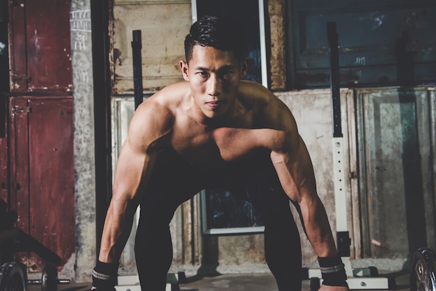 Retrato del primer de un entrenamiento del hombre muscular con el barbell en el gimnasio local