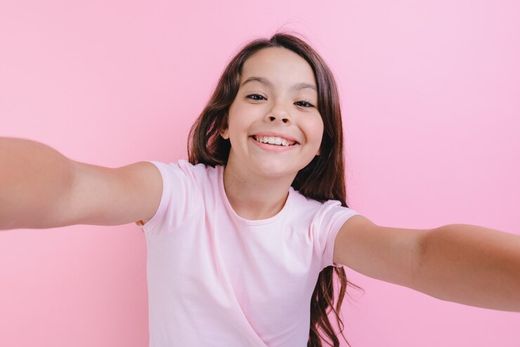Foto retrato del primer de una muchacha alegre sobre el studiowith rosado que endereza las manos