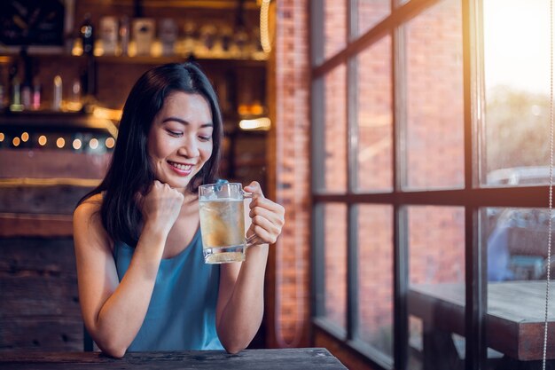 Retrato del primer, mujer atractiva que goza bebiendo la cerveza dentro de la barra.