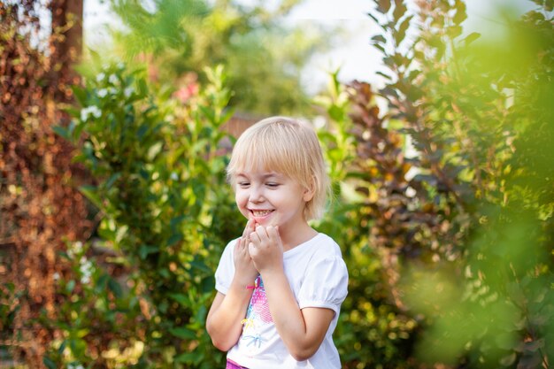 Retrato del primer de la pequeña muchacha feliz de Blobde en edad de escuela primaria al aire libre en parque verde