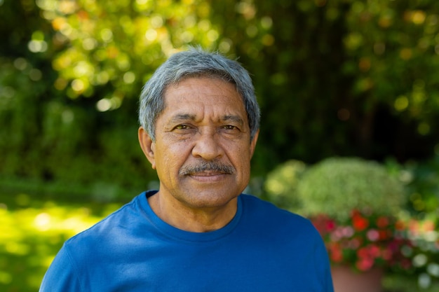 Retrato de primer plano de un anciano birracial confiado que usa ropa deportiva contra plantas en el patio