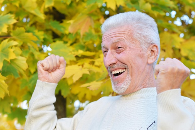 Retrato de primer plano de un anciano feliz posando en el parque de otoño