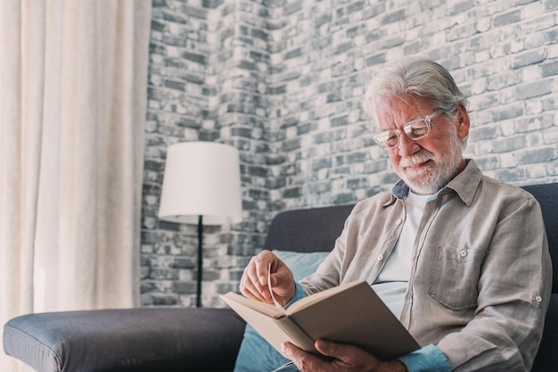 Retrato en primer plano de un anciano feliz y relajado sentado leyendo un libro en casa Hombre maduro
