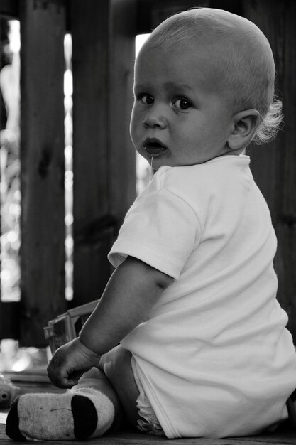 Retrato en primer plano de un bebé lindo sentado en la mesa en casa