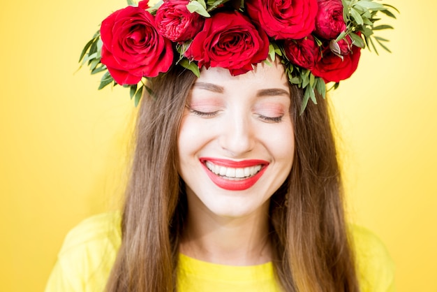 Retrato de primer plano de una bella mujer con corona de rosas rojas sobre fondo amarillo