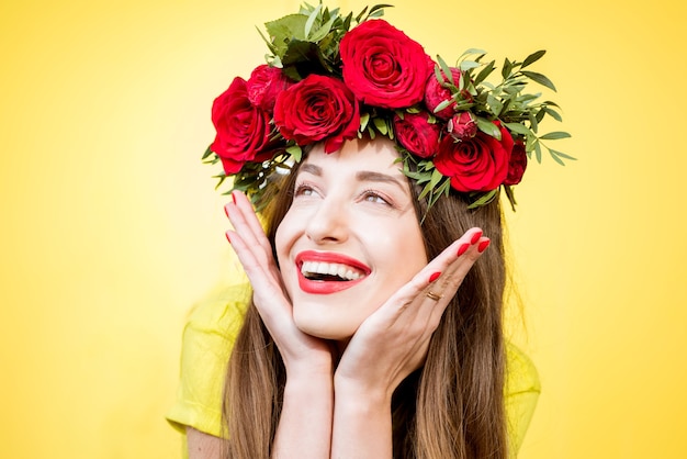 Retrato de primer plano de una bella mujer con corona de rosas rojas sobre fondo amarillo