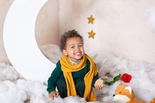 Un retrato de primer plano de la cara de un niño afroamericano. El niño pequeño se sienta y sonríe. Bebé lindo, bebé en el juego. Sonrisa bonita. Pelo RIZADO. Infancia. El niño juega en el jardín de infantes. Educación preescolar infantil