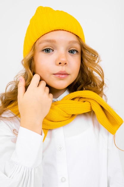 Retrato de primer plano de una chica atractiva con un sombrero amarillo y una camisa blanca con una sudadera atada sobre sus hombros