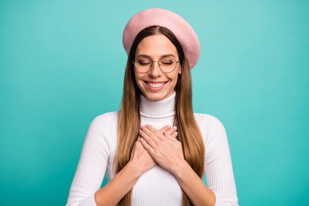 Retrato de primer plano de la chica de pelo lacio de ensueño alegre atractivo agradable sosteniendo las manos cruzadas en el corazón encantado de buenas noticias complacidas aisladas sobre fondo de color azul vibrante de brillo vivo brillante