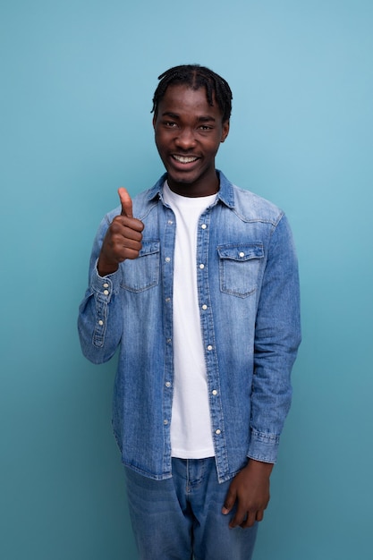 Retrato de primer plano de un chico africano de moda genial con rastas en una chaqueta de mezclilla con perspicacia