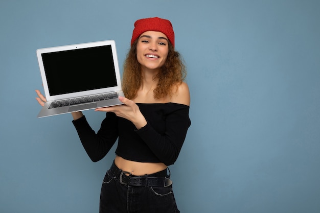 Retrato de primer plano de divertido sonriente feliz hermosa joven rubia oscura sosteniendo la computadora portátil