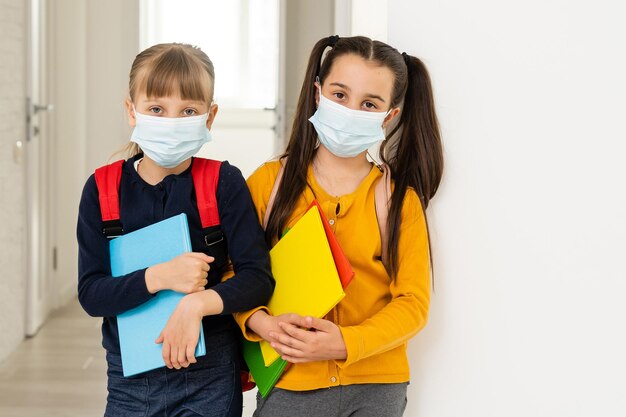 Retrato de primer plano de dos chicas atractivas y agradables con máscara de seguridad. detener la pandemia de la enfermedad de la gripe.