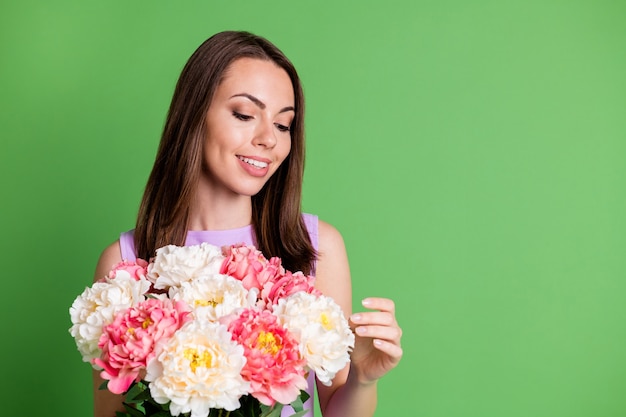 Retrato de primer plano de ella ella agradable atractiva bastante encantadora alegre alegre chica disfrutando de las vacaciones del día de San Patricio sosteniendo en las manos manojo de flores frescas copia espacio aislado fondo de color verde