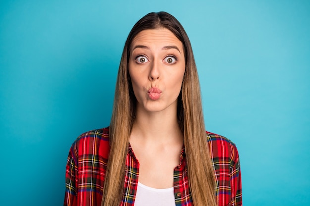 Retrato de primer plano de ella ella bonita atractiva bastante encantadora linda adorable divertida chica de pelo largo vistiendo camisa a cuadros enviando beso de aire aislado sobre fondo de color azul vibrante brillante brillo vivo