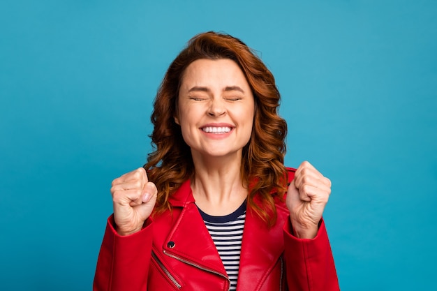 Foto retrato de primer plano de ella ella bonita atractiva encantadora alegre alegre afortunada chica de pelo ondulado sosteniendo puños disfrutando de suerte aislado sobre fondo de color azul vibrante brillante brillo vivo