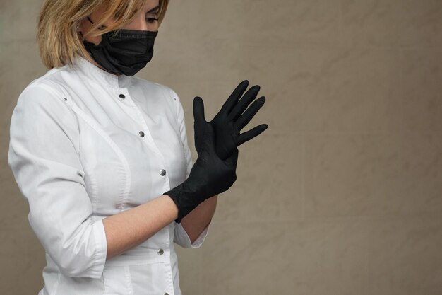 Foto retrato en primer plano de una esteticista con guantes médicos negros y máscara médica negra