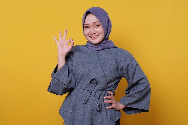 Retrato de primer plano de feliz joven asiática vistiendo hijab mostrando diciendo gesto bien