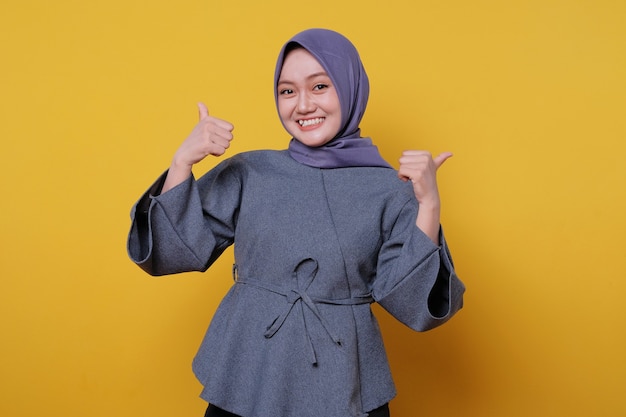 Retrato de primer plano de feliz joven asiática vistiendo hijab mostrando el pulgar hacia arriba gesto