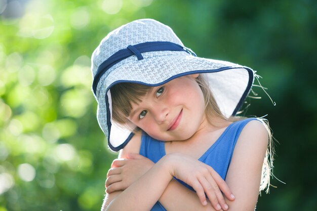 Retrato de primer plano de feliz niña sonriente en un gran sombrero. Niño que se divierte al aire libre en verano.