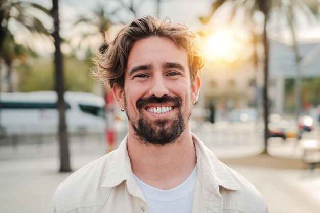 Retrato en primer plano de un guapo hombre barbudo con dientes blancos perfectos sonriendo y mirando a la cámara