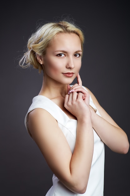 Retrato de primer plano de hermosa modelo con largo cabello rubio sobre fondo negro