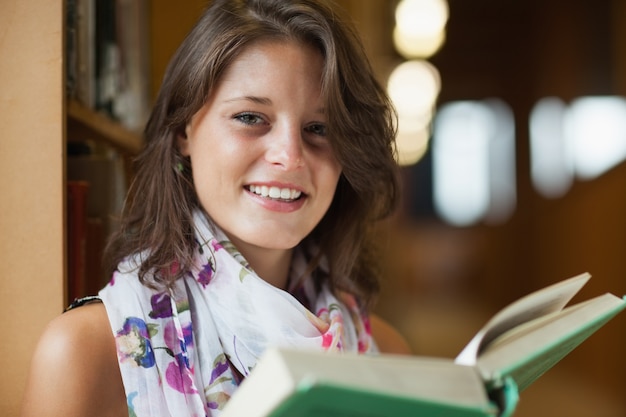 Retrato de primer plano de una hermosa mujer sonriente sosteniendo un libro