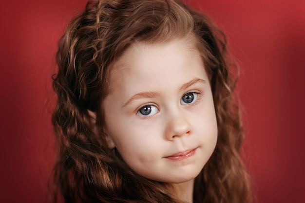 Retrato de un primer plano de una hermosa niña con el pelo rizado. Mira a la cámara