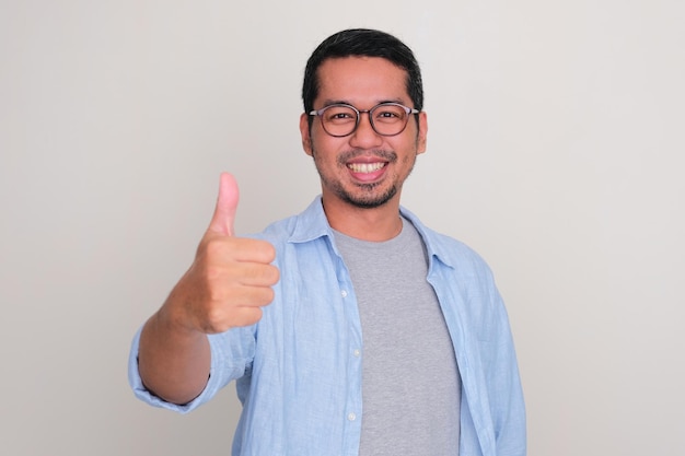 Retrato en primer plano de un hombre asiático sonriente con el pulgar en alto