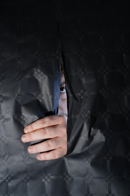 Foto retrato en primer plano de un hombre mirando a través de una tela rasgada