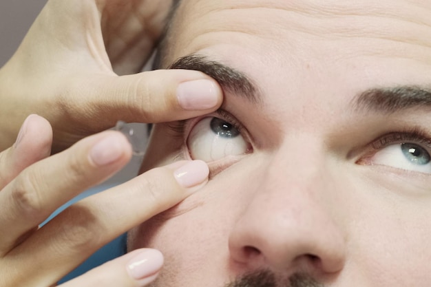 Retrato de primer plano de un hombre sentado en la oficina de un optometrista mientras el médico examina su visión y se pone lentes en una clínica moderna