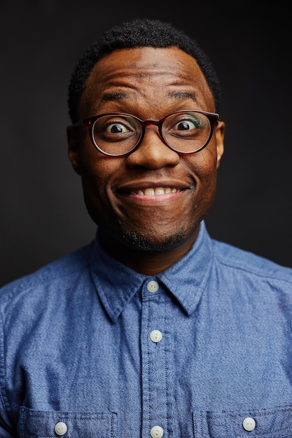 Retrato en primer plano de un hombre sonriente con gafas contra un fondo negro