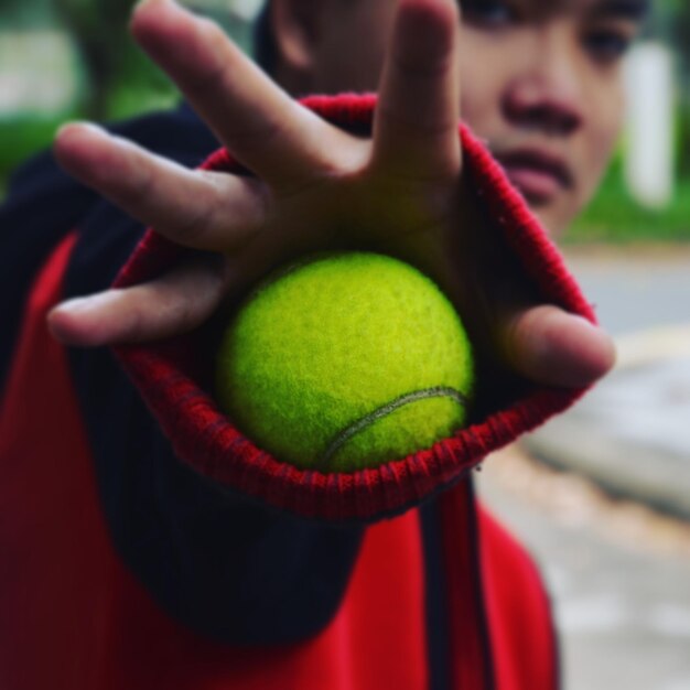 Foto retrato en primer plano de un hombre sosteniendo una pelota de tenis mientras está de pie al aire libre