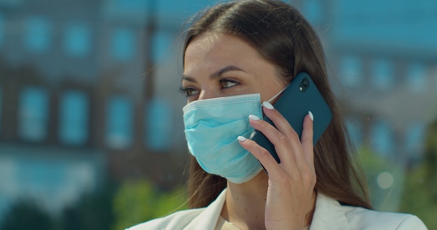 Foto retrato de primer plano de joven en mascarilla médica está hablando por teléfono.