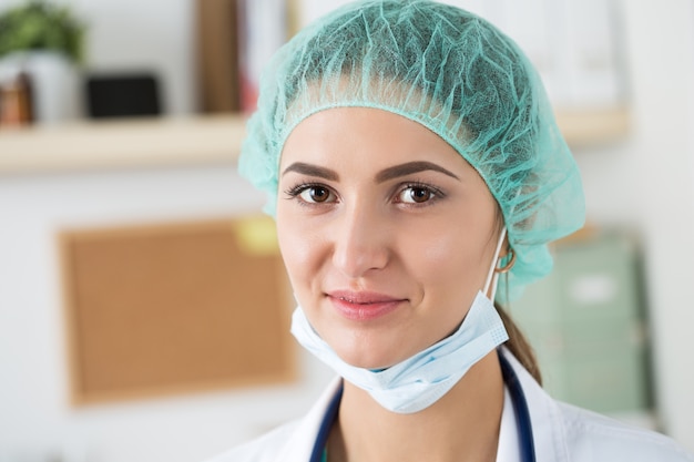 Retrato de primer plano de joven médico cirujano o pasante con máscara protectora y sombrero. Cuidado de la salud, educación médica, servicio médico de emergencia, cirugía o concepto veterinario