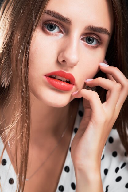 Retrato de primer plano de una joven con el pelo largo y labios rojos.