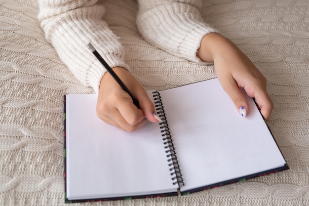 Retrato de primer plano de una joven relajada escribiendo un libro mientras está acostada en la cama Foto de alta calidad