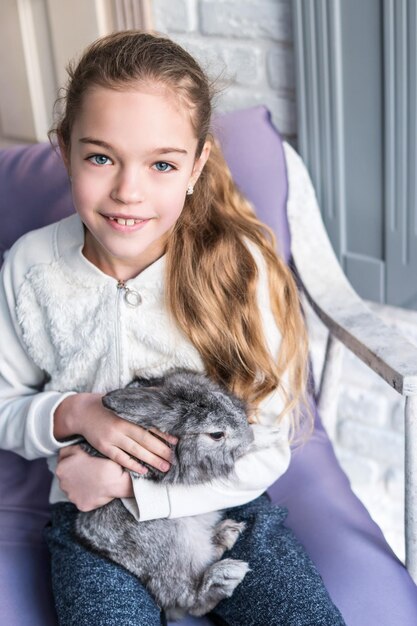 Retrato de primer plano de una linda chica con un conejo en las manos