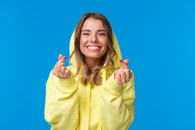 Retrato de primer plano de linda y tonta rubia caucásica en sudadera con capucha amarilla