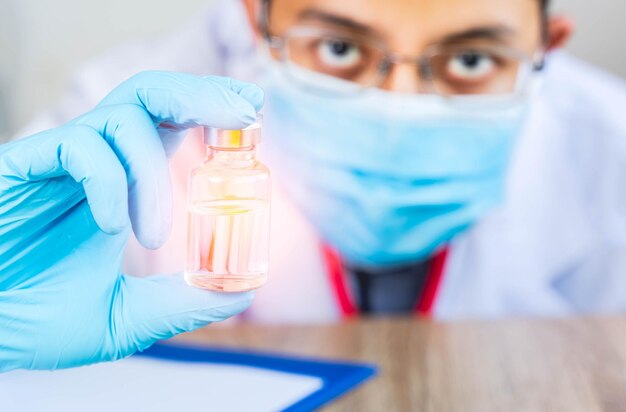 Foto retrato en primer plano del médico que sostiene el vial en el laboratorio