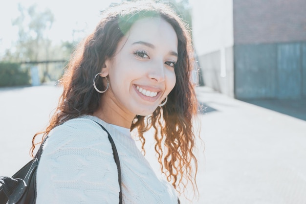 Un retrato de primer plano de una mujer africana mirando a la cámara y sonriendo. La ropa es un clásico blanco más dulce. Estudiante en el concepto de universidad, feliz aprendizaje, día soleado