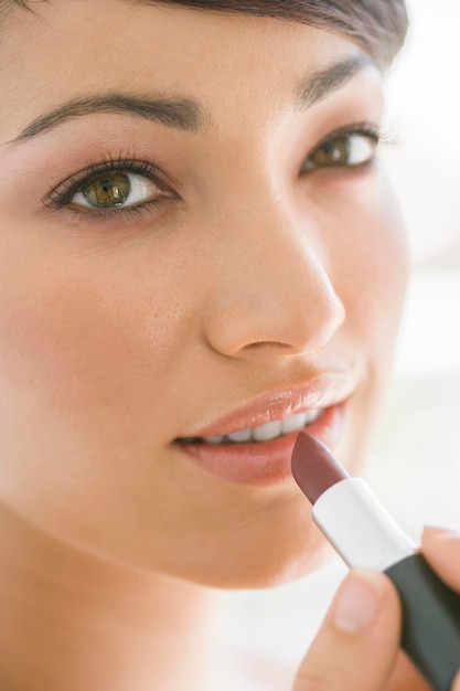 Retrato en primer plano de una mujer aplicando lápiz labial