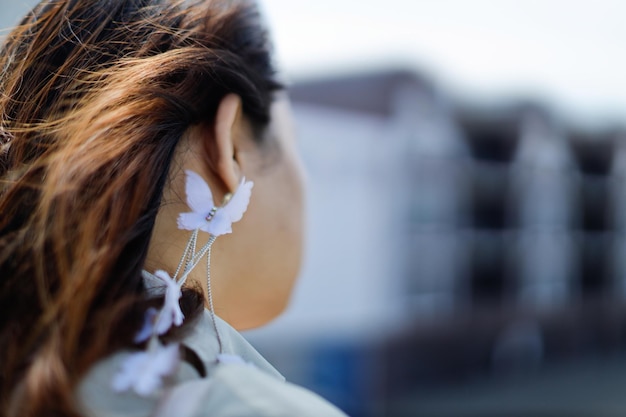 Retrato en primer plano de una mujer enfocada en pendientes de mariposa